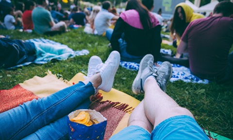 Event Image, people laying on a picnic blanket in a crowd